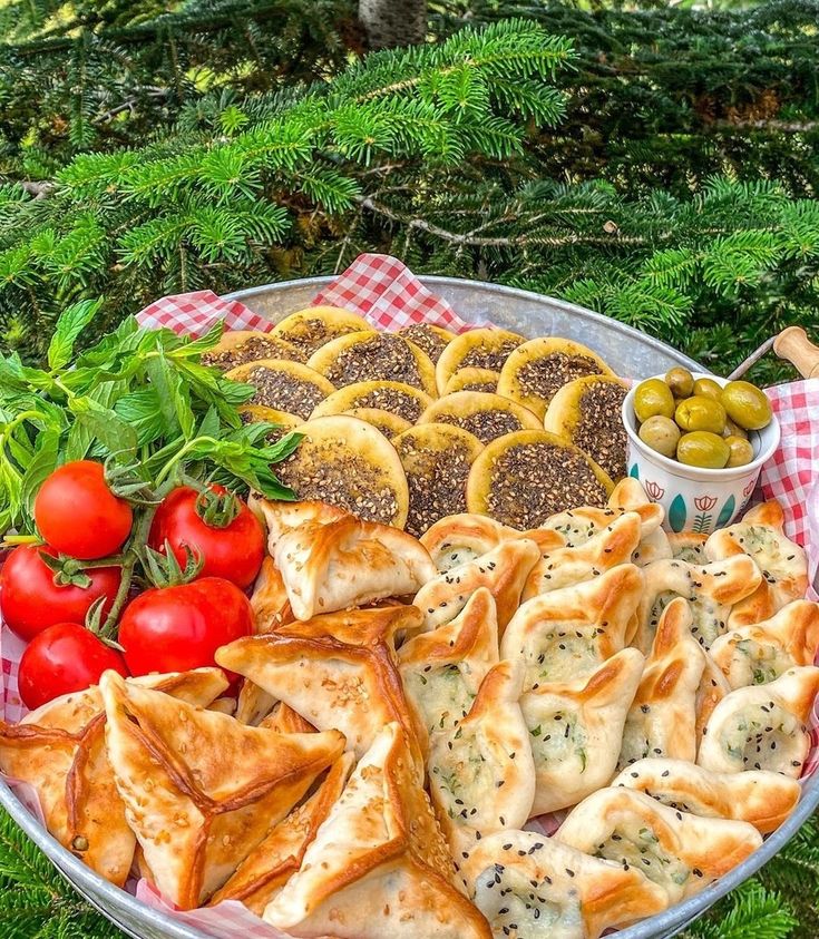 a platter full of appetizers with tomatoes, olives and crackers