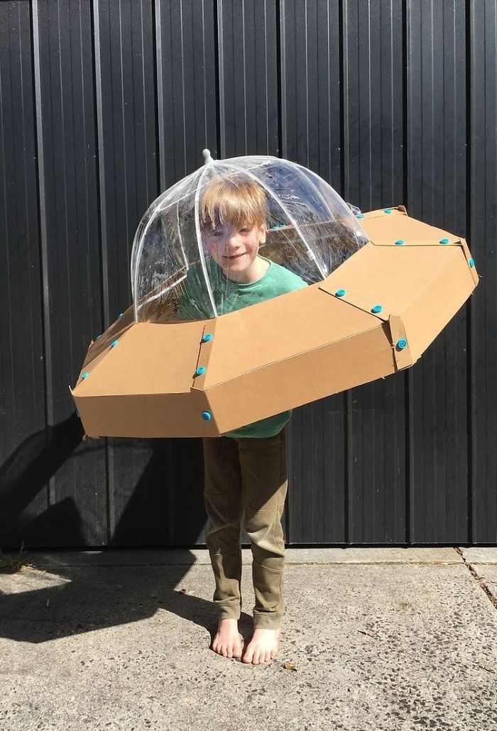 a young boy is holding an umbrella made out of cardboard and it's attached to a box