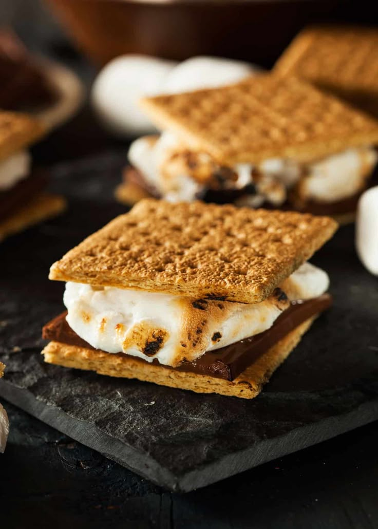 s'mores on a slate board with marshmallows in the background