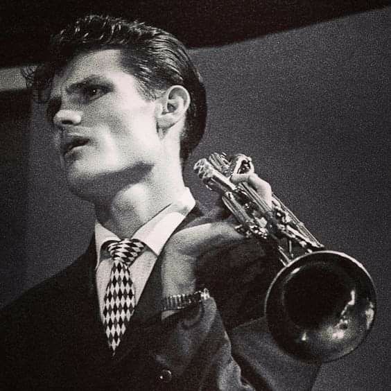 a man in a suit and tie holding a trumpet