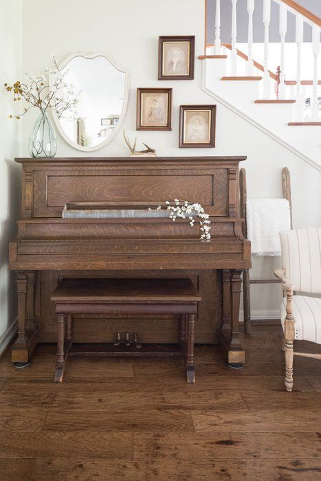 a grand piano sitting in the corner of a living room next to a stair case