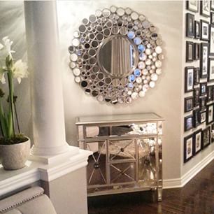 a living room with pictures on the wall and a mirror over the fireplace mantel