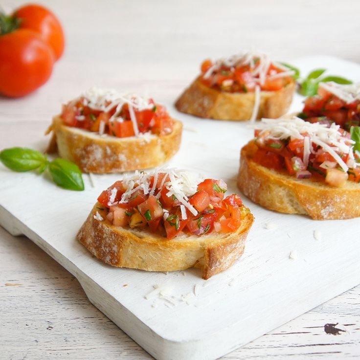 small appetizers with tomato sauce and parmesan cheese on a cutting board