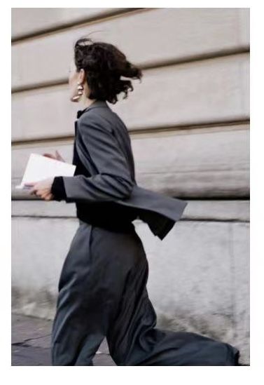 a woman is walking down the street carrying papers