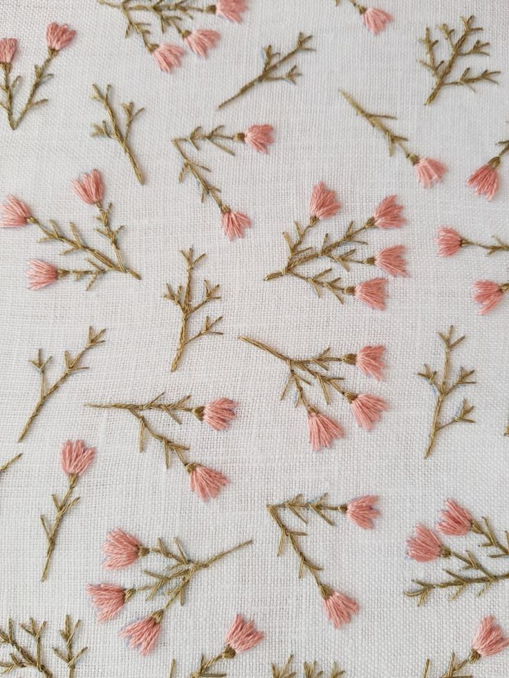 pink flowers are embroidered on white fabric