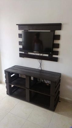 a flat screen tv sitting on top of a wooden entertainment center next to a window