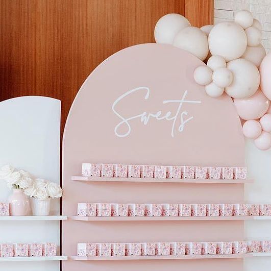 there is a pink and white display with balloons on the wall next to some shelves