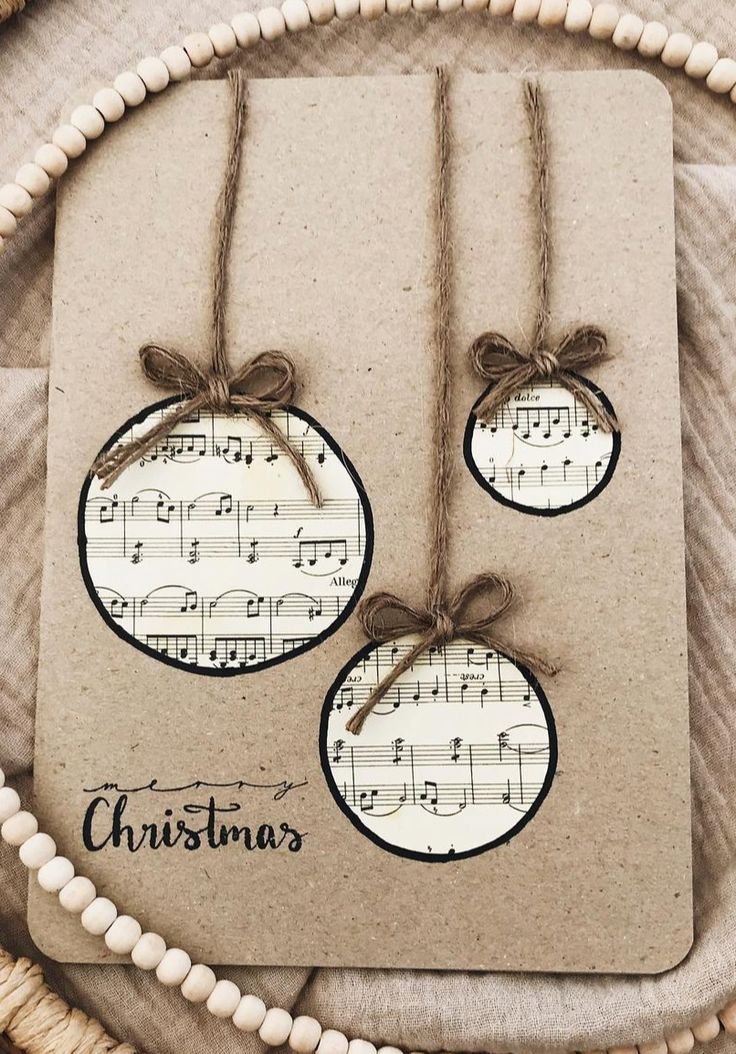 three ornaments are hanging from twine strings on a piece of paper that says christmas