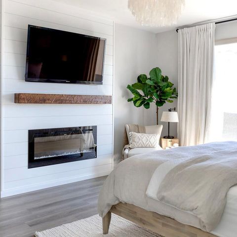 a bedroom with a bed, fireplace and tv mounted on the wall in it's corner