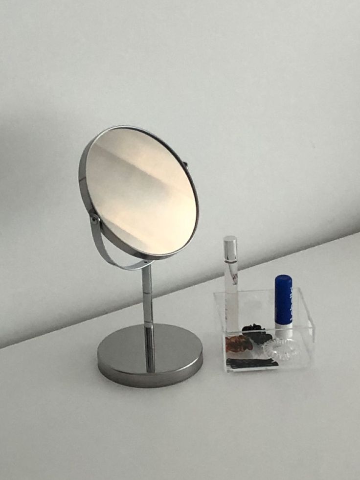 a small mirror sitting on top of a table next to a tube of toothpaste