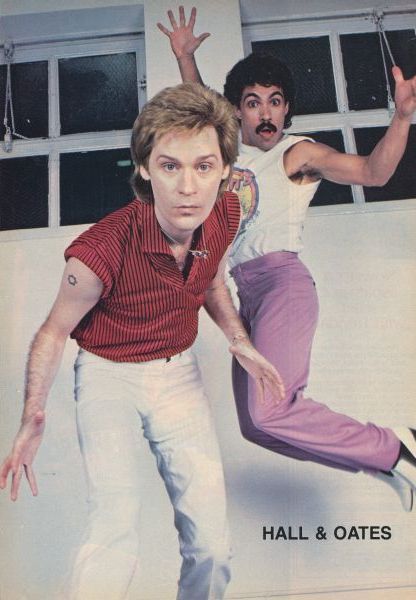 an old photo of two men jumping in the air with their hands up and one man holding his leg out