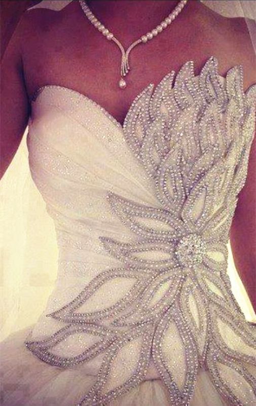 a woman wearing a wedding dress with beading on it