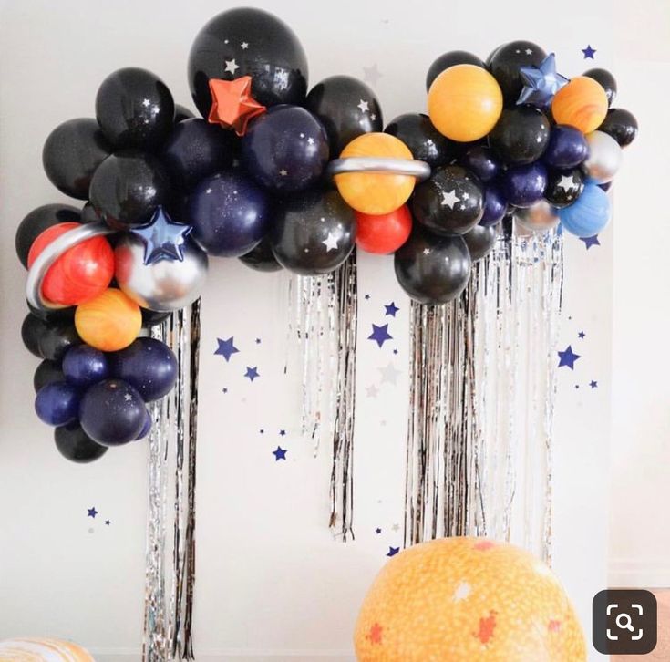 an assortment of balloons are hanging on the wall in front of a balloon arch that is decorated with stars and stripes