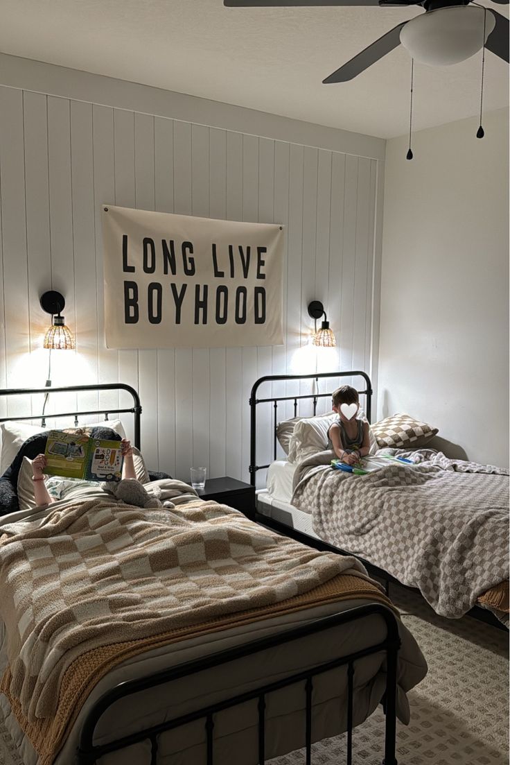 two beds in a room with white walls and black metal frames, one has a girl reading on the bed