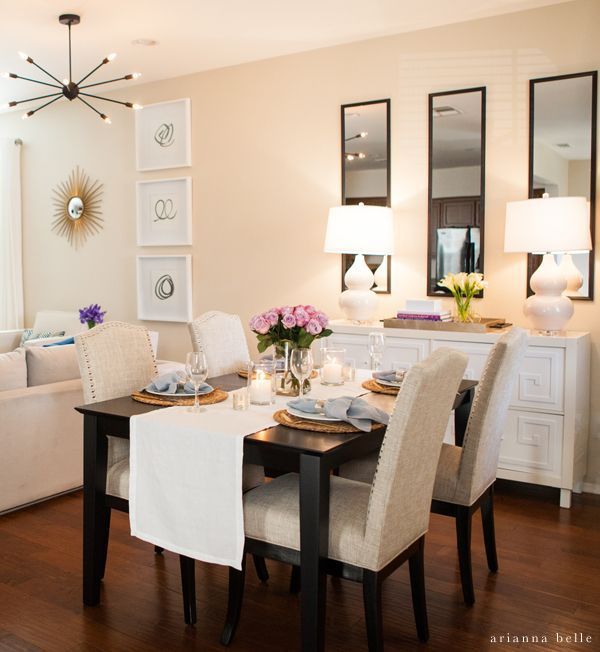 a dinning room table set with place settings and flowers in vases on it