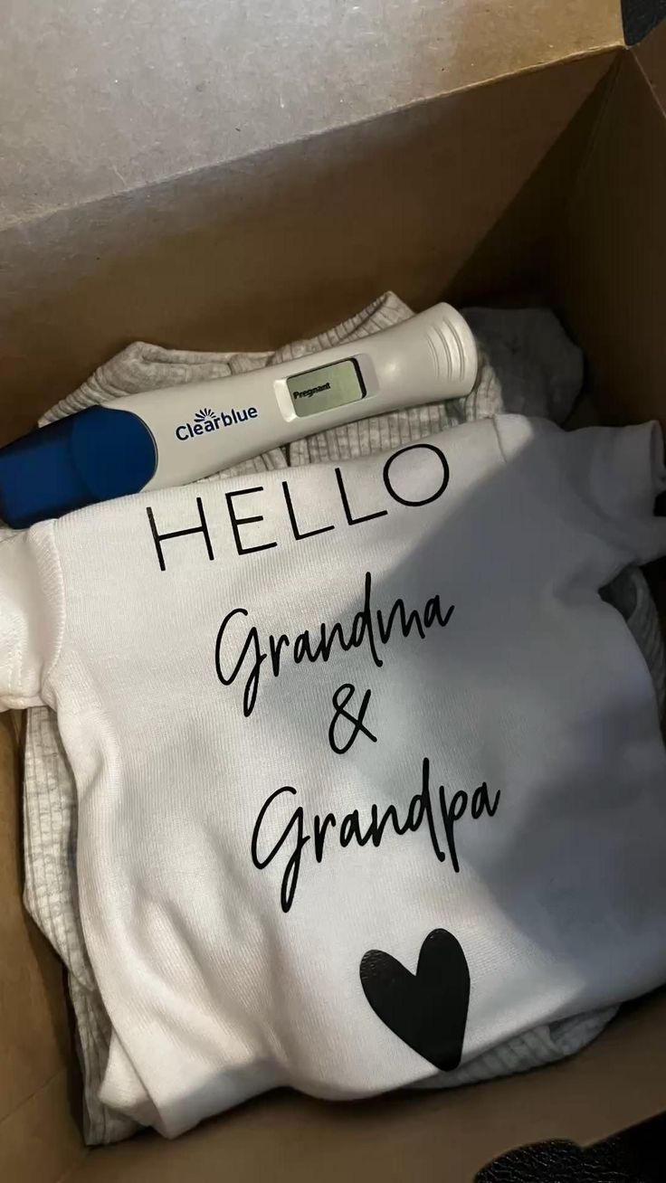 a baby's shirt in a box with the words hello grandma and grandpa written on it