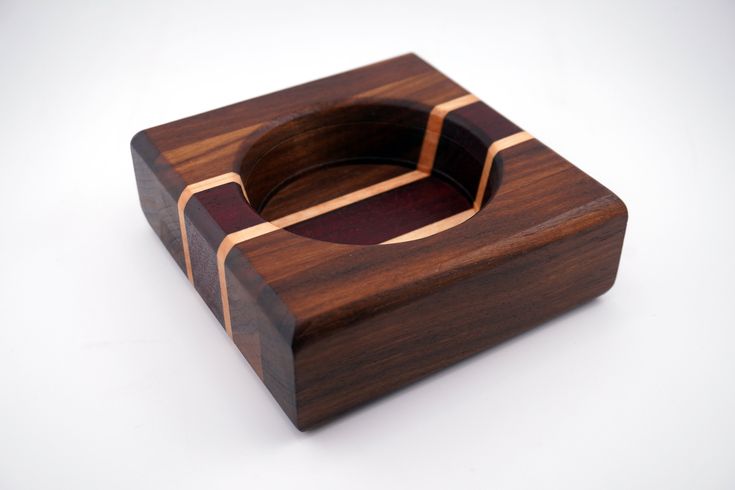 a small wooden box with an unusual design on the front and sides, sitting on a white surface