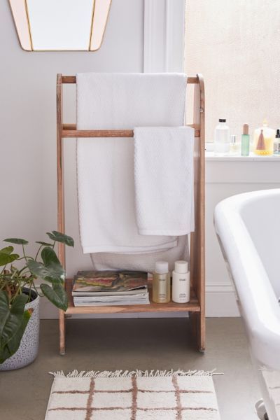 a bathroom with a towel rack and bathtub in the corner, next to a potted plant