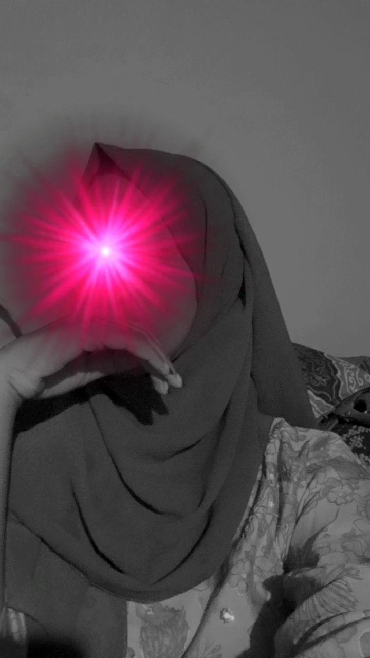 a woman wearing a hijab with a red light on her face in front of her head