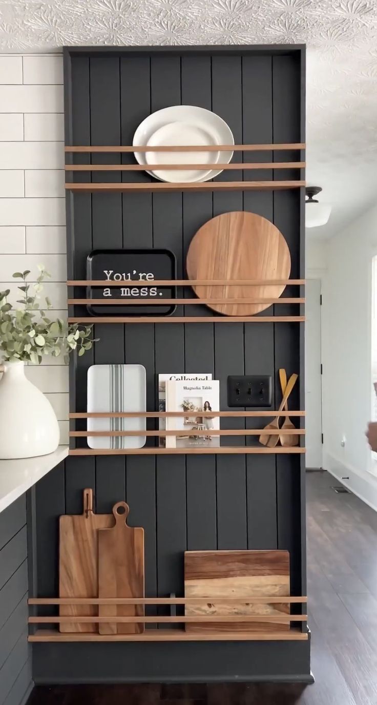 the shelves in this kitchen are organized with wooden cutting boards, plates and utensils