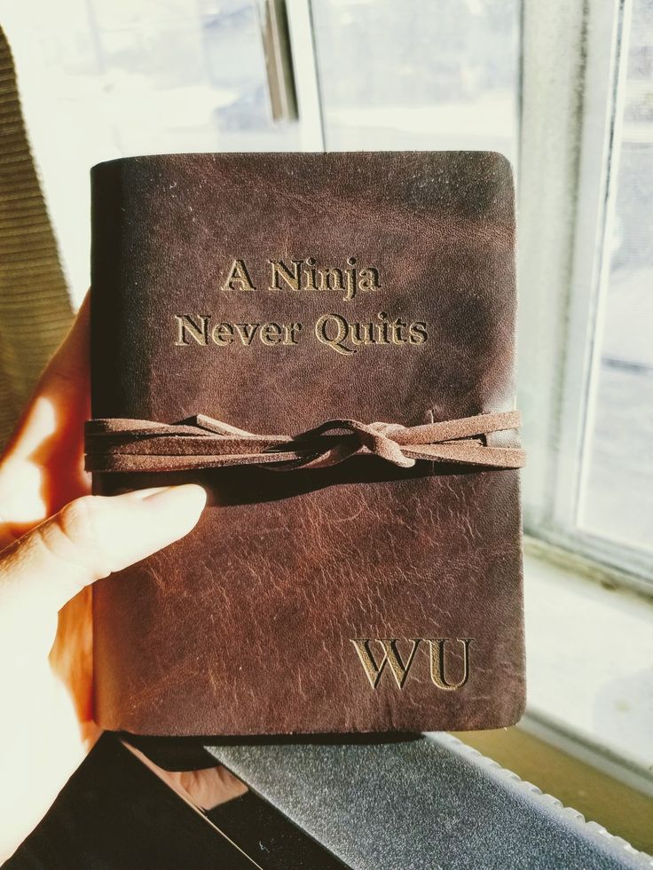 a person holding up a brown book with the words a nifta never quits written on it