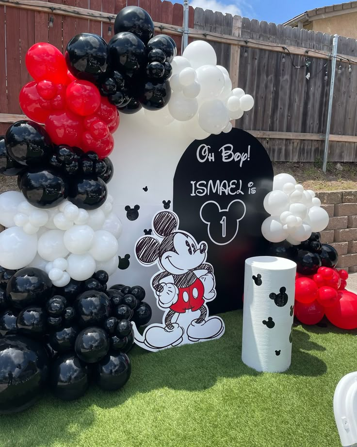 mickey mouse themed birthday party with balloon decorations and black and white balloons on the grass