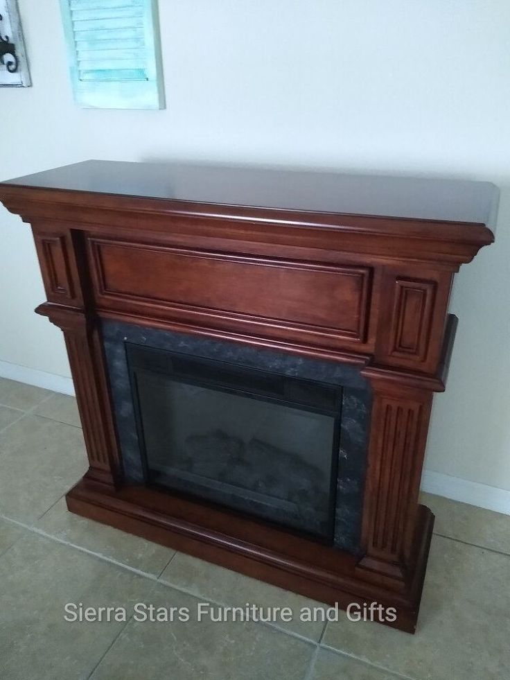 an empty fireplace in a living room with tile flooring and white wall behind it