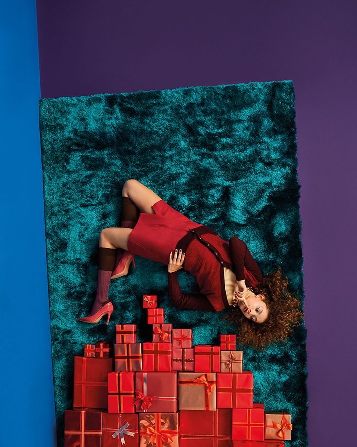 a woman laying on top of a green carpet next to a red brick wall and floor