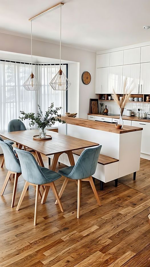 a kitchen with wooden floors and white cabinetry has a dining table surrounded by blue chairs