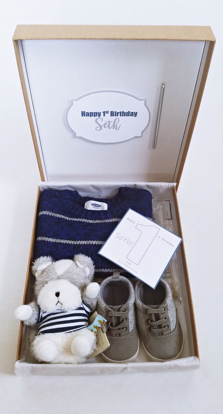 a white teddy bear sitting in a box with shoes and a sweater on it's lap