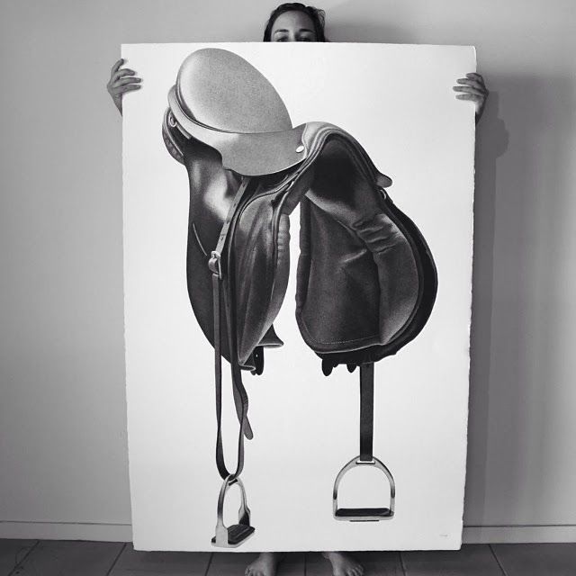 a woman holding up a poster with a horse saddle on it