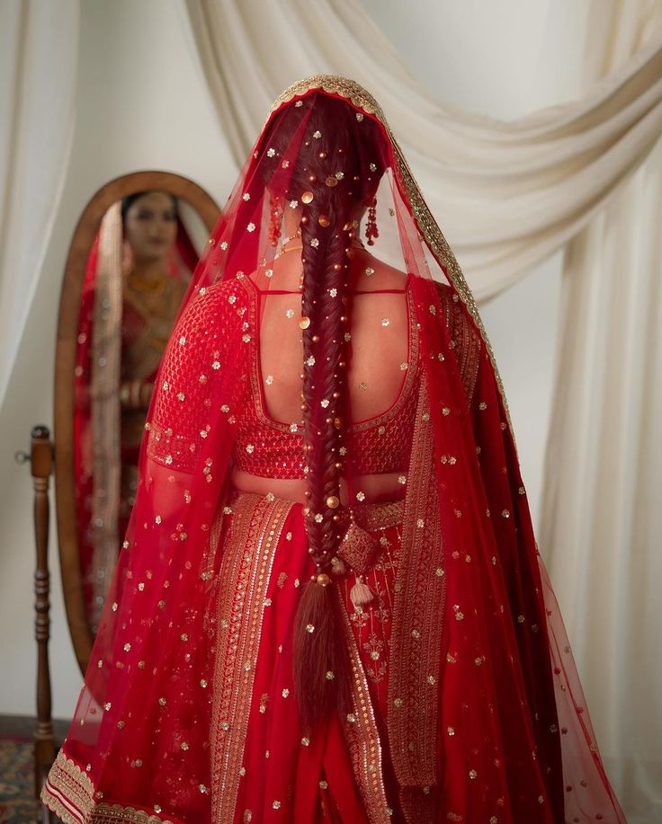 a woman wearing a red bridal gown and veil