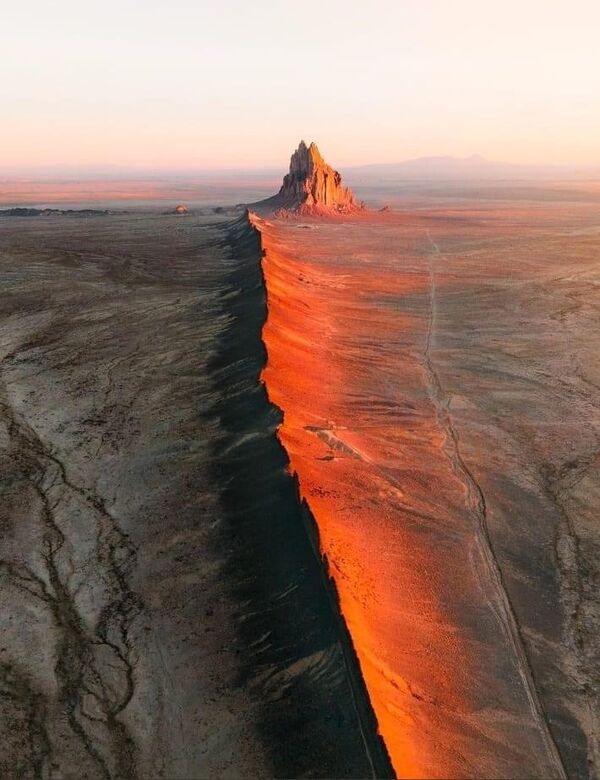 an aerial view of the desert with a mountain in the distance and water running through it