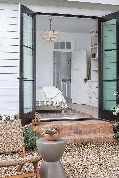 an open door leading to a bedroom with a bed in the background and a chair outside