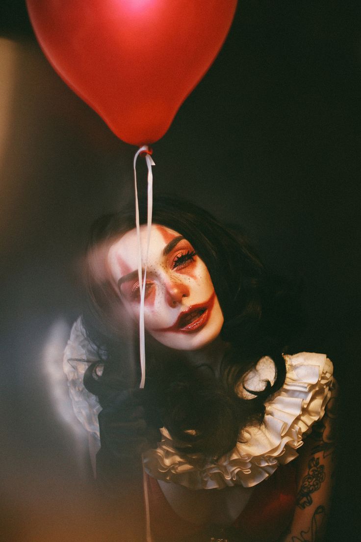 a woman holding a red balloon up to her face