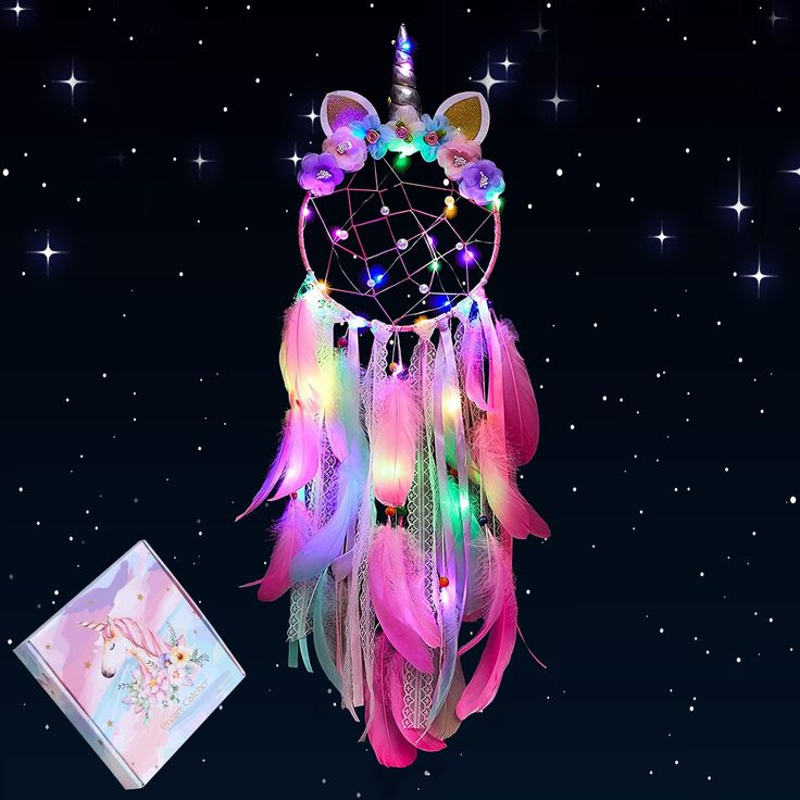 a pink and blue dream catcher with lights on it next to a notepad that says happy new year