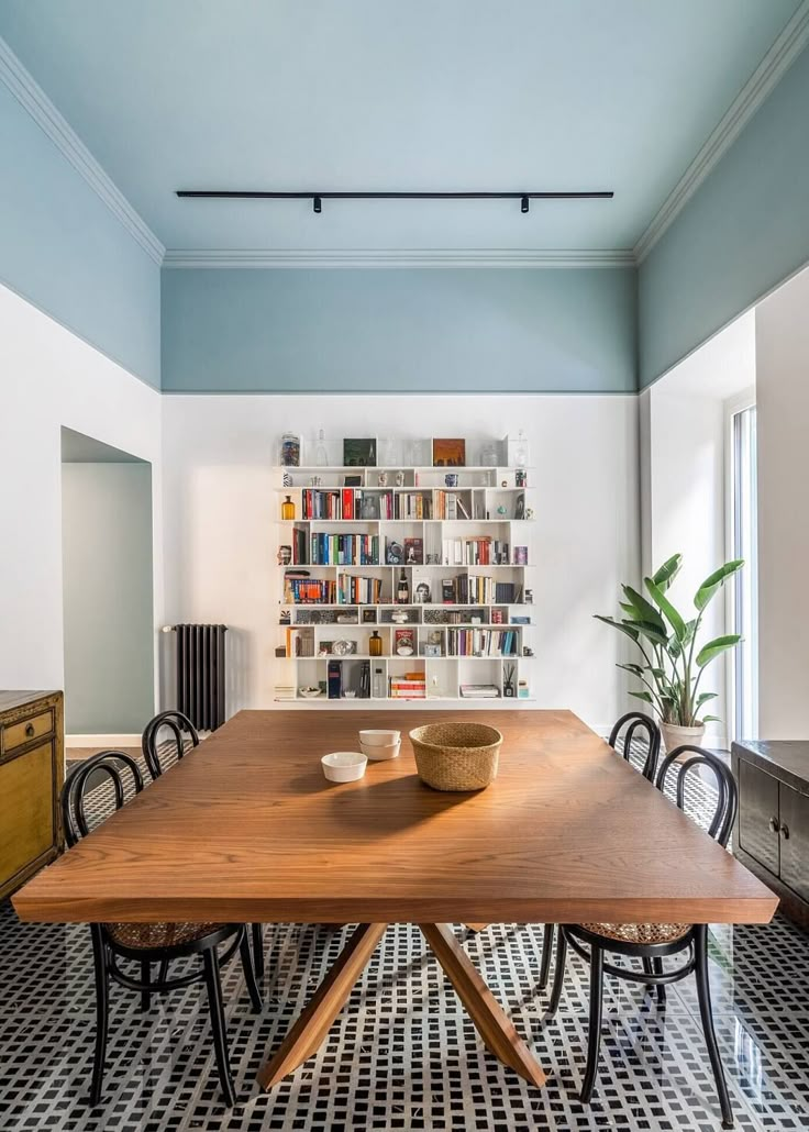 a wooden table sitting in the middle of a room with black and white flooring