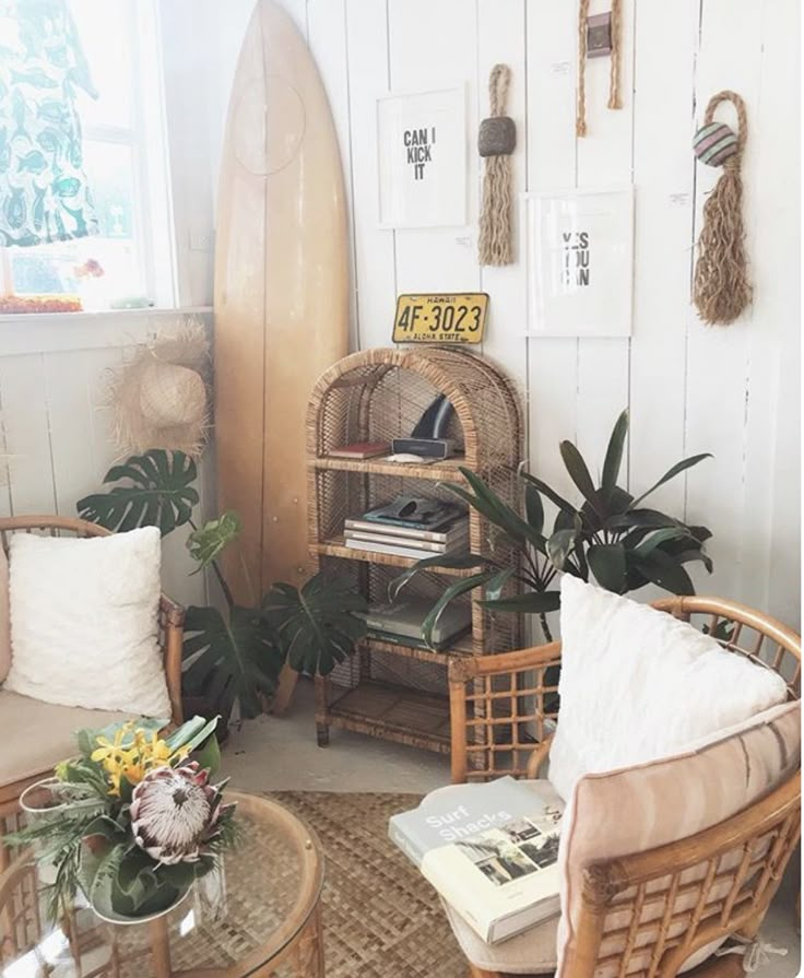 a living room with wicker furniture and surfboards on the wall behind it,