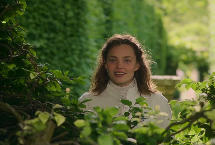 a woman standing in the middle of some bushes