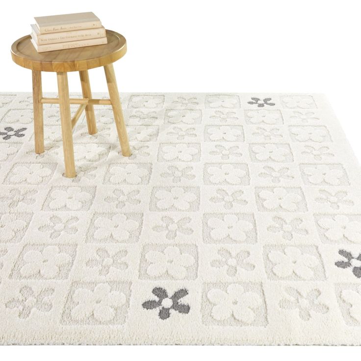 a white rug with black and grey flowers on it, next to a small table