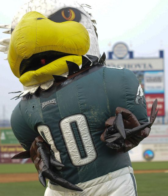 an eagle mascot is standing in the outfield at a baseball game with his hands on his hips