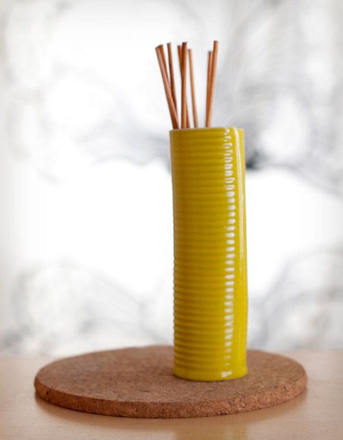 a yellow vase with sticks sticking out of it