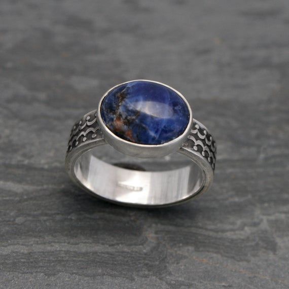 Blue Planet Sodalite Sterling Silver RingGorgeous deep blue oval sodalite set in solid sterling silver.  The thick sterling silver ring band is decorated with a scalloped design.  Antiqued finish on the ring band shows off the detailed design.Sodalite is 1/2" x 3/8".  Ring band is 1/4" wide.  Ring Size 7. One of a kind. You may also like:https://www.etsy.com/shop/KiraFerrer/search?search_query=ringsℴ=date_desc&view_type=gallery&ref=shop_searchTo see my entire collection:http://www.etsy.c Blue Domed Gemstone Ring, Blue Cabochon Rings, Unique Blue Cabochon Ring, Blue Sodalite Ring, Blue Sodalite Jewelry, Marauders Dr, Silver Ring Band, Scalloped Design, Blue Planet