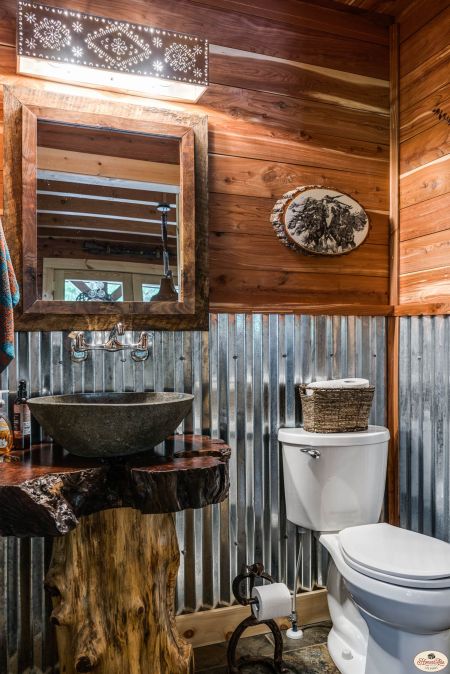 a bathroom with a toilet, sink and mirror in the corner next to a tree stump