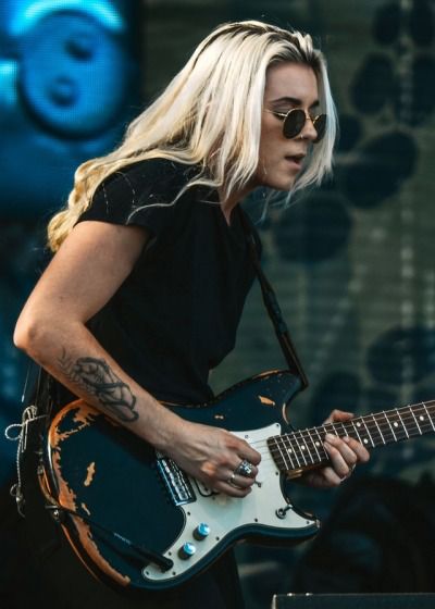 a woman with blonde hair playing an electric guitar