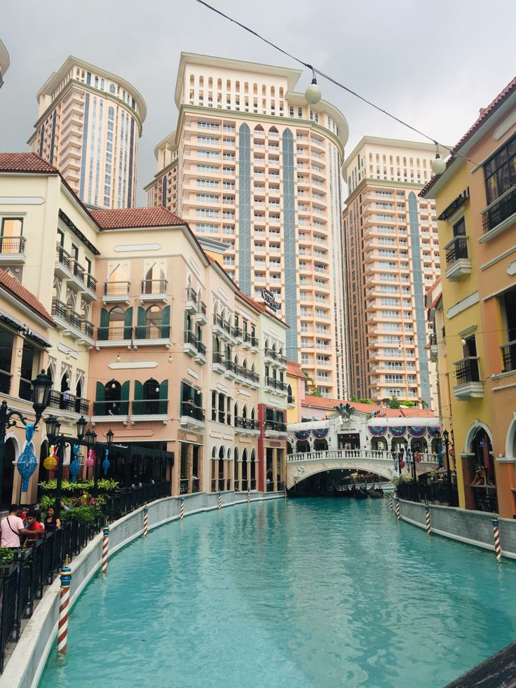 an outdoor shopping area in the middle of a large body of water surrounded by tall buildings