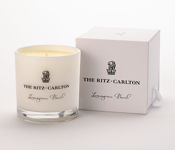 the ritz - carlton candle is next to a box on a white tablecloth