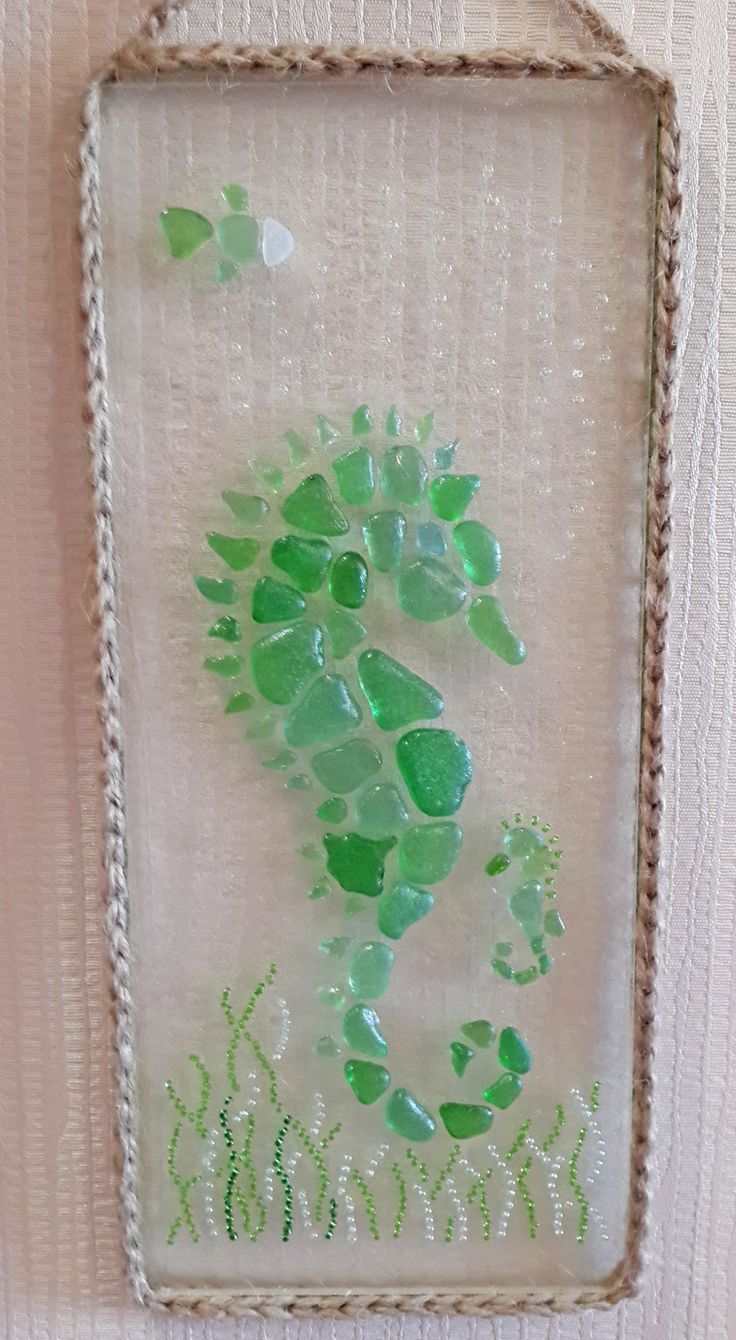 a glass frame hanging on the wall with green leaves and grass in front of it