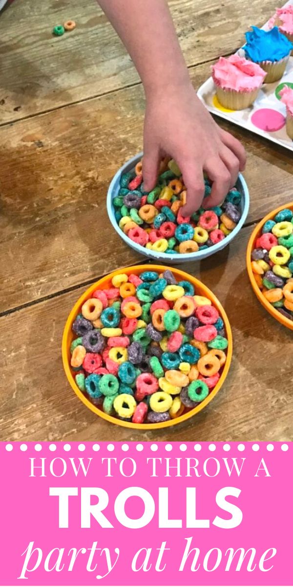 two bowls filled with colorful sprinkles on top of a wooden table next to cupcakes