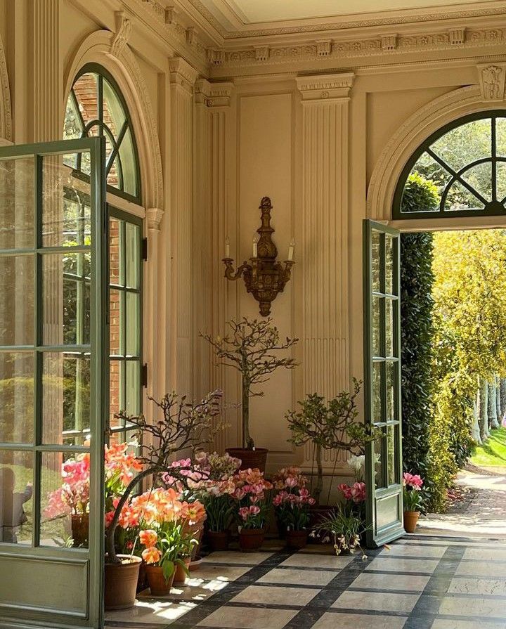 an open door leading into a large room with potted plants on either side of it